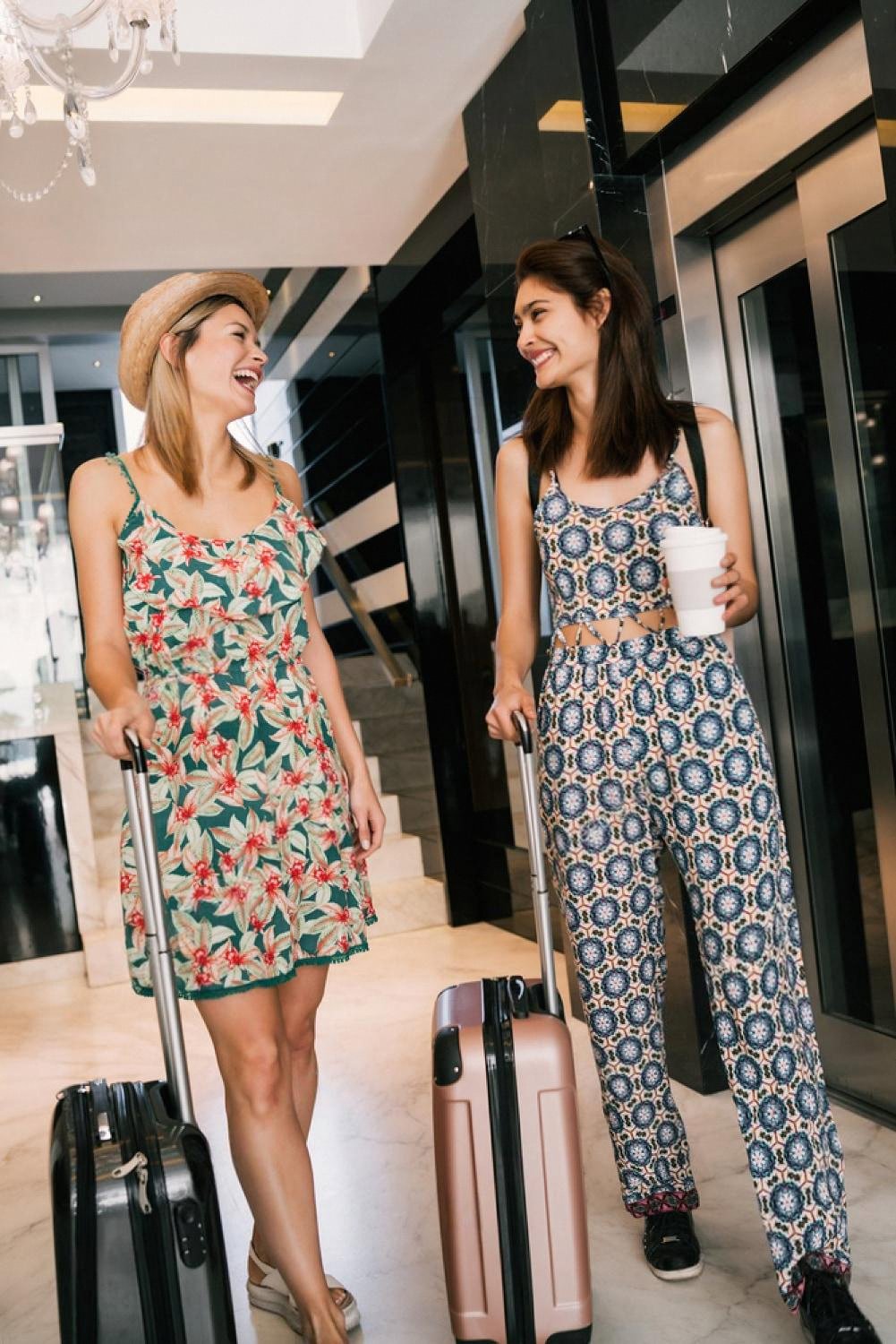 Two women with suitcases arriving at a Dubai hotel lobby after online check-in